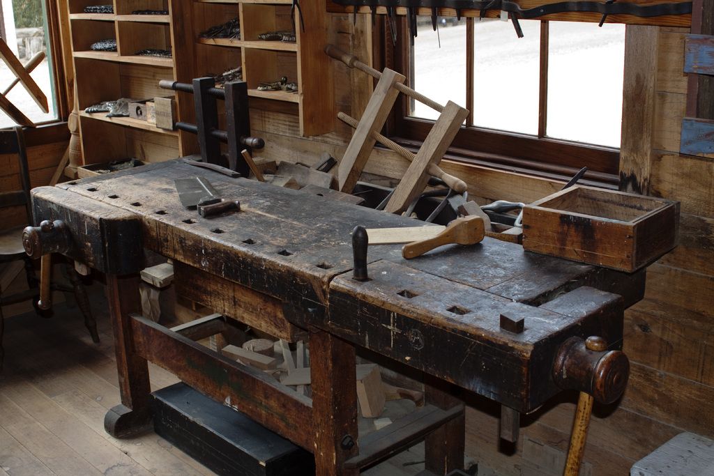 A well-used wooden workbench with hand tools in a carpentry workshop